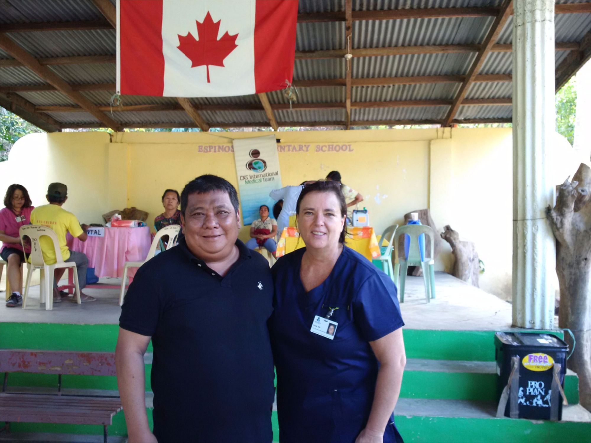 Patient and nurse posing for a picture under a canadian flag at a community nursing event